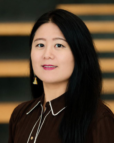 Ginger Chen | ISDC 2026 Portrait of an East Asian woman with long black hair, wearing a brown blouse and tassel earrings.