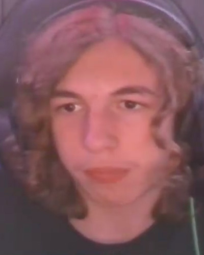 Portrait of a young person with shoulder-length wavy hair wearing headphones, facing the camera.