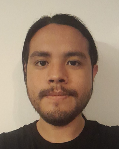 Tyee Garcia | ISDC 2026 Close-up portrait of a man with dark hair and a short beard, wearing a black shirt, against a light background.