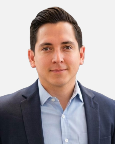 Professional headshot of a man in a navy blazer and light blue shirt, looking at the camera with a neutral expression.