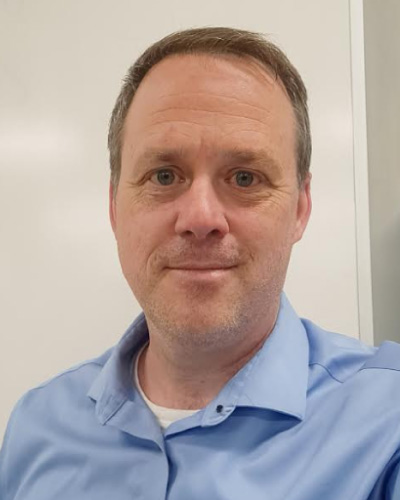 Michael Johnson | ISDC 2026 Head-and-shoulders portrait of a middle-aged man with short brown hair in a light blue collared shirt, looking at the camera.