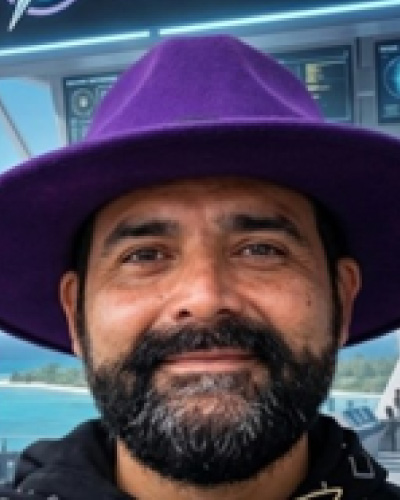 Alejandro-Merle-Otero | ISDC Close-up of a man wearing a purple wide-brimmed hat, smiling on a boat with the ocean in the background.